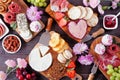 Mothers Day charcuterie table with a dark wood background. Selection of cheeses, meats, fruit and sweets.