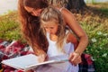 Mother`s day, Women`s day. Woman and her kids with grandmother reading books. Family having picnic in park Royalty Free Stock Photo