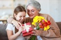 Mother`s and grandmothers day! family granddaughter congratulates her grandmother on holiday and gives flowers and gifts