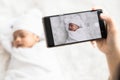 Mother `s hand holding smartphone use to taking photo cute newborn baby for memories and pose in social network