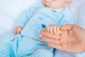 Mother`s hand holds a cute little baby in her hand at home on the bed Royalty Free Stock Photo