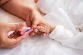 The mother`s hand holds a nail clipper, and the other hand holds the newborn`s hand, Mom carefully cuts the baby`s nails one na Royalty Free Stock Photo