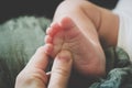 Mother`s hand massaging tiny infant baby feet.
