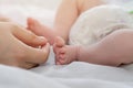 Mother`s hands near the little feet of her newborn baby. Mom and Child. A beautiful conceptual image of motherhood Royalty Free Stock Photo