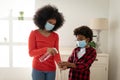 Mother sanitizing hands of her son at home