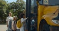 Mother saying goodbye little son standing at bus. Pupils boarding schoolbus. Royalty Free Stock Photo