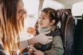 Mother securing her toddler daughter buckled into her baby car seat Royalty Free Stock Photo