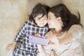Mother is selfie with her little daughter using a smart phone camera while kissing daughter cheek. Royalty Free Stock Photo