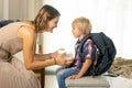 Mother, sending her firstgrader boy to school, first day at school, giving him books and a box with snack