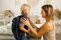 Mother, sending her firstgrader boy to school, first day at school, giving him books and a box with snack