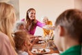 Mother Serving Food As Multi-Generation Family Meet For Meal At Home