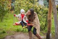 Mother shakes her baby on swing at the autumn park. Happy family spend time together Royalty Free Stock Photo