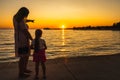 Mother showing her daughter a beautiful sunset at the beach while holding hands Royalty Free Stock Photo