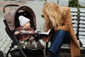 Mother sitting on the bench and showing something for her little child in a book Royalty Free Stock Photo