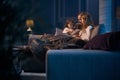 Mother sitting on couch with two daughters and reading book