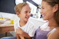 Mother Sitting With Laughing Son At Breakfast Table