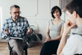 Mother sitting next to handsome therapist talking to her teenage child