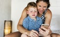 Mother sitting with son on bed using mobile Royalty Free Stock Photo