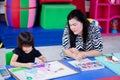 Mother is sitting and watching or encouraging her daughter to paint her own painting. Concept of activities to promote learning in Royalty Free Stock Photo