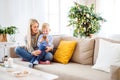 A mother and small boy with smartphone sitting on a sofa at home at Christmas time. Royalty Free Stock Photo