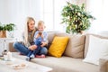 A mother and small boy with smartphone sitting on a sofa at home at Christmas time.