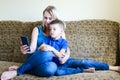 Mother and small child, boy at home sitting on couch, using digital tablet, relax. Working on mobile phone from home. Happy family Royalty Free Stock Photo