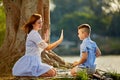 Mother and small son play with sand. Baby hold her hands to the mothers arms. Active parents and people outdoor activity Royalty Free Stock Photo