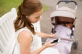 Mother with smartphone, earphones and stroller Royalty Free Stock Photo