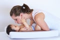 Mother, smile and baby kiss at home on diaper changing table with happiness. Family, house and young child with mom