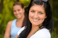 Mother smiling with teen daughter in background