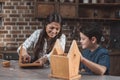 Little son and his beautiful mother crafting a wooden birdhouse