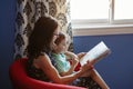 Mother with son boy sitting in armchair at home and reading book together. Child kid early development and education. Family mom Royalty Free Stock Photo