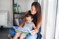 Mother with son boy sitting on floor at home and reading book together. Child kid early development education. Family mom and baby Royalty Free Stock Photo