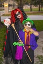 Mother and son in bright colored Halloween costumes standing at door trick r treating in neighborhood