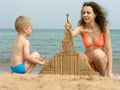 Mother with son build sand building on beach