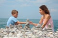 Mother and son builds stone stacks on beach Royalty Free Stock Photo