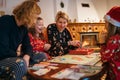 Mother, son and daughters kids playing together table board game, wearing Christmas hats. Cozy pre Christmas evening time moment