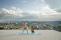 Mother and son doing exercise on the balcony in the background of a city during sunrise or sunset, concept of a healthy lifestyle Royalty Free Stock Photo