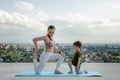 Mother and son doing exercise on the balcony in the background of a city during sunrise or sunset, concept of a healthy lifestyle Royalty Free Stock Photo