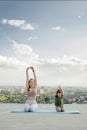 Mother and son doing exercise on the balcony in the background of a city during sunrise or sunset, concept of a healthy lifestyle Royalty Free Stock Photo