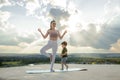 Mother and son doing exercise on the balcony in the background of a city during sunrise or sunset, concept of a healthy lifestyle Royalty Free Stock Photo