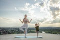 Mother and son doing exercise on the balcony in the background of a city during sunrise or sunset, concept of a healthy lifestyle Royalty Free Stock Photo