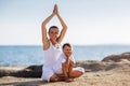 A mother and a son are doing yoga exercises at the seashore of M Royalty Free Stock Photo