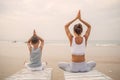 A mother and a son are doing yoga exercises at the seashore of tropic ocean Royalty Free Stock Photo