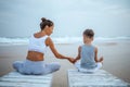 A mother and a son are doing yoga exercises at the seashore of tropic ocean Royalty Free Stock Photo