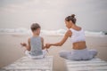 A mother and a son are doing yoga exercises at the seashore of tropic ocean Royalty Free Stock Photo