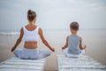 A mother and a son are doing yoga exercises at the seashore of tropic ocean Royalty Free Stock Photo