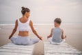 A mother and a son are doing yoga exercises at the seashore of tropic ocean Royalty Free Stock Photo