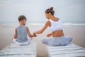 A mother and a son are doing yoga exercises at the seashore of tropic ocean Royalty Free Stock Photo