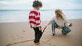 Mother son drawing beach with sticks on autumn weekend. Family playing seaside Royalty Free Stock Photo